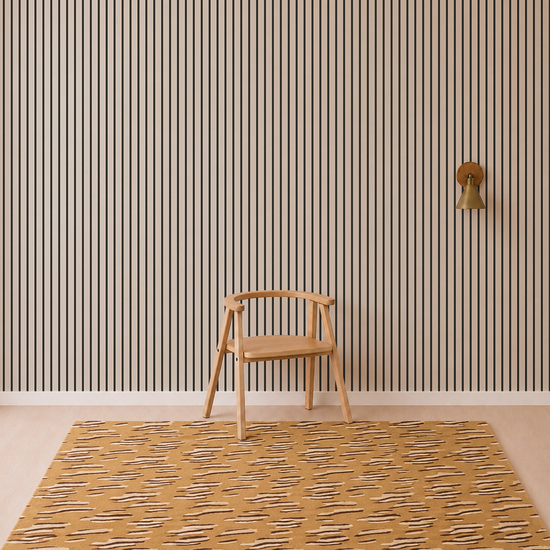 A wooden chair sits on a mustard and beige patterned rug in front of a tan wall decorated with the Pinstripe Wallpaper Charcoal, next to a brass wall sconce.