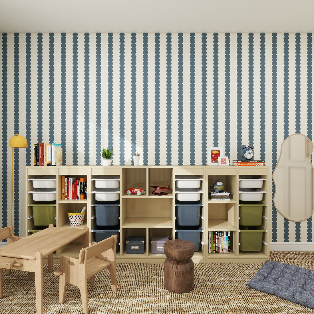 A nursery playroom features wood furniture, open cubby storage with bins, books, toys, a small table with chairs, a brown pouf, and Scallop Stripe Wallpaper Deep Blue adding charm to the wall.