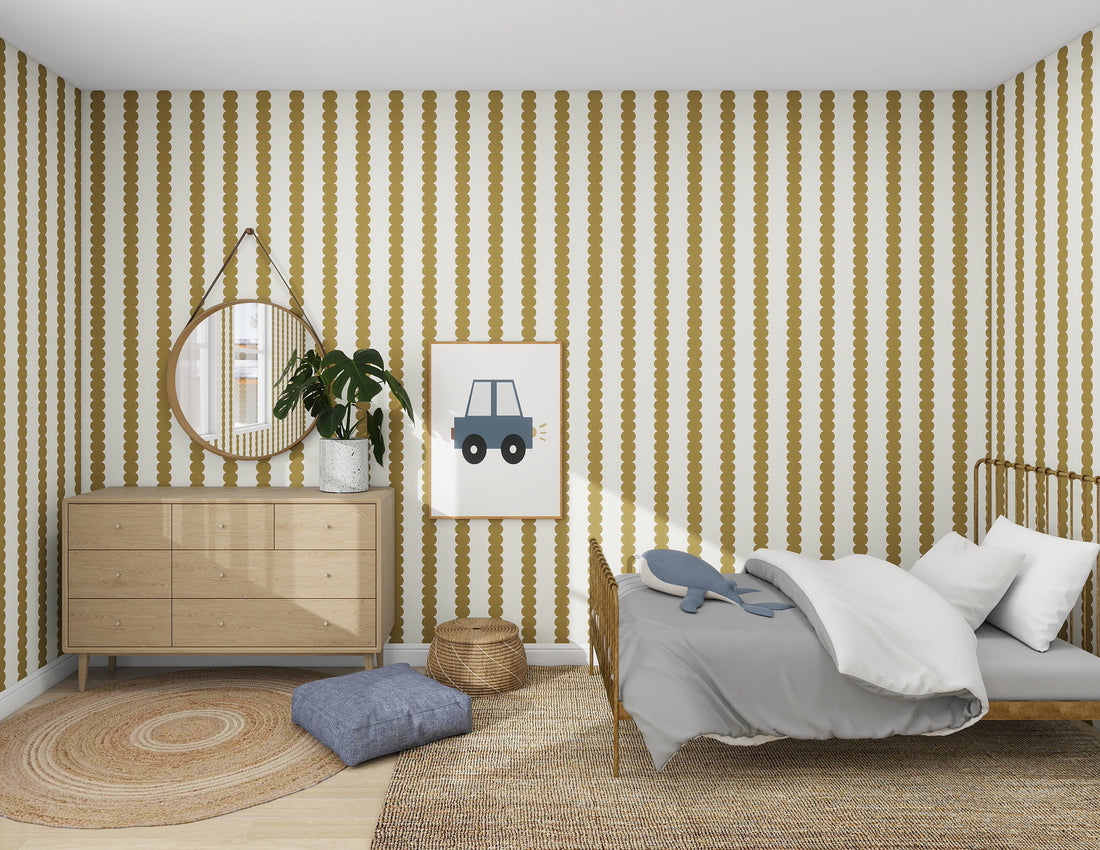 A bedroom with Munks and Mes Scallop Stripe Wallpaper in Moss has a wooden bed with gray bedding, a dresser with a round mirror, a potted plant, framed car print, a round rug, and floor cushions.