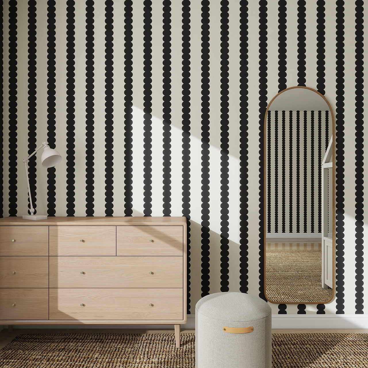 A room featuring a dresser, floor lamp, ottoman, and an arched mirror reflecting Scallop Stripe Wallpaper Charcoal on the walls. The floor is covered with a textured woven rug.