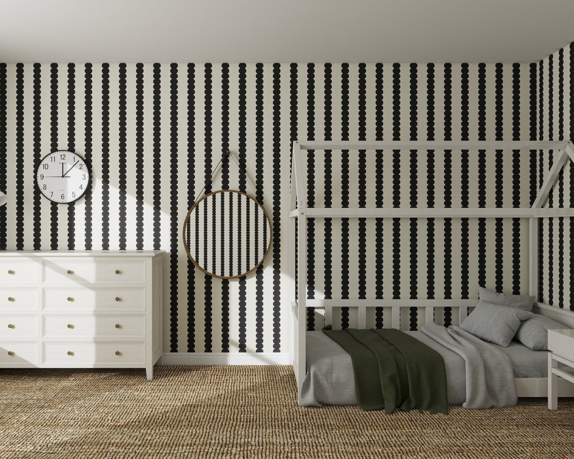 A bedroom featuring bold black and white Scallop Stripe Wallpaper Charcoal, a white dresser with gold knobs, a round mirror, a white bunk bed with gray bedding, and a brown woven rug on the floor.