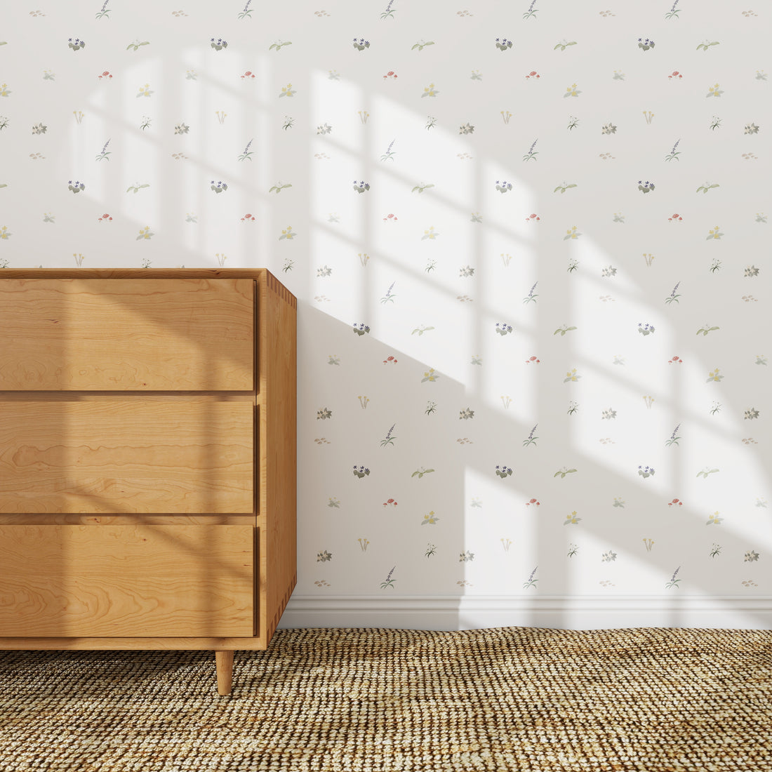 The Mollys Flower Garden Wallpaper Repeat | Sample adds a delicate floral touch to the white wall behind a light wooden dresser, with sunlight casting windowpane shadows across both the wallpaper and dresser for an inviting look.