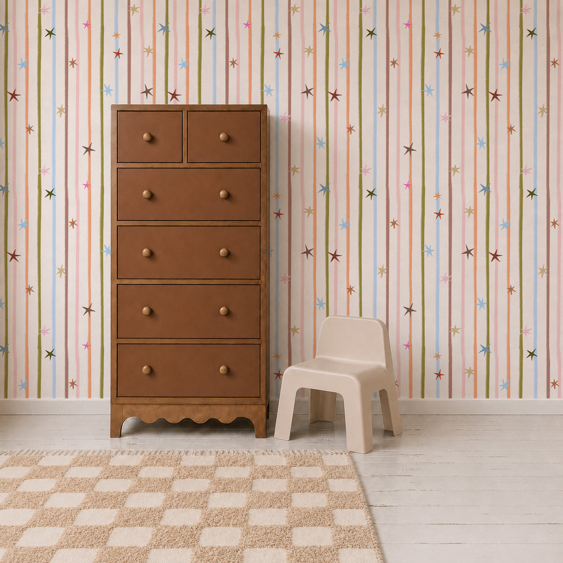A wooden dresser and small plastic chair sit in front of Starlight Stripe Wallpaper, which features vertical multicolored stripes and small star motifs.