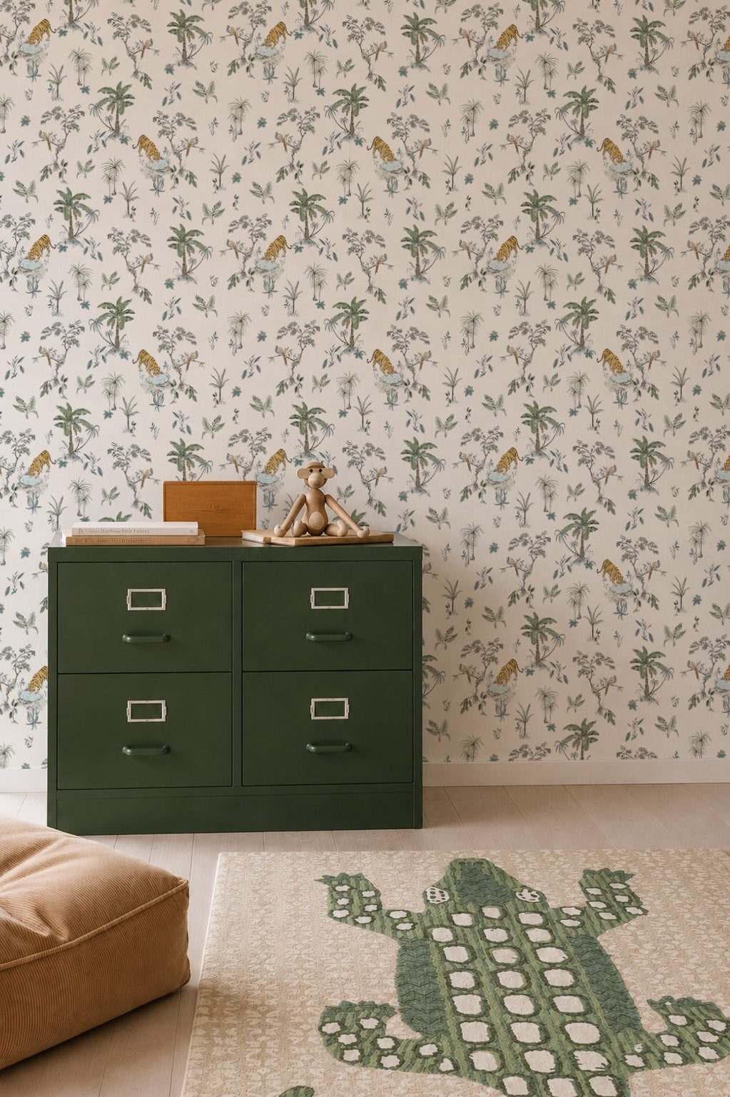 A children’s room with the Tropical Tiger Wallpaper Sample, a dark green dresser with toys, a tan floor cushion, and a rug showcasing a large green crocodile.