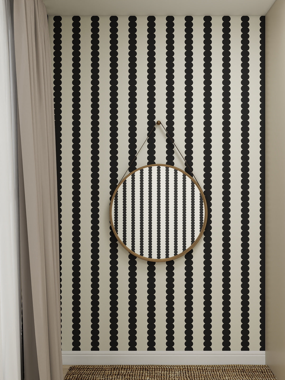 A round mirror with a thin black frame hangs on a wall clad in Scallop Stripe Wallpaper, Charcoal. Beige curtains are on the left, and a woven rug partially covers the floor, completing this chic monochrome space.
