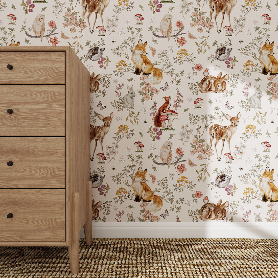 A wooden chest of drawers sits on a woven rug by a wall decorated with Whimsical Woodland Wallpaper, which features woodland animals—deer, foxes, rabbits, and birds—amid flowers and mushrooms.