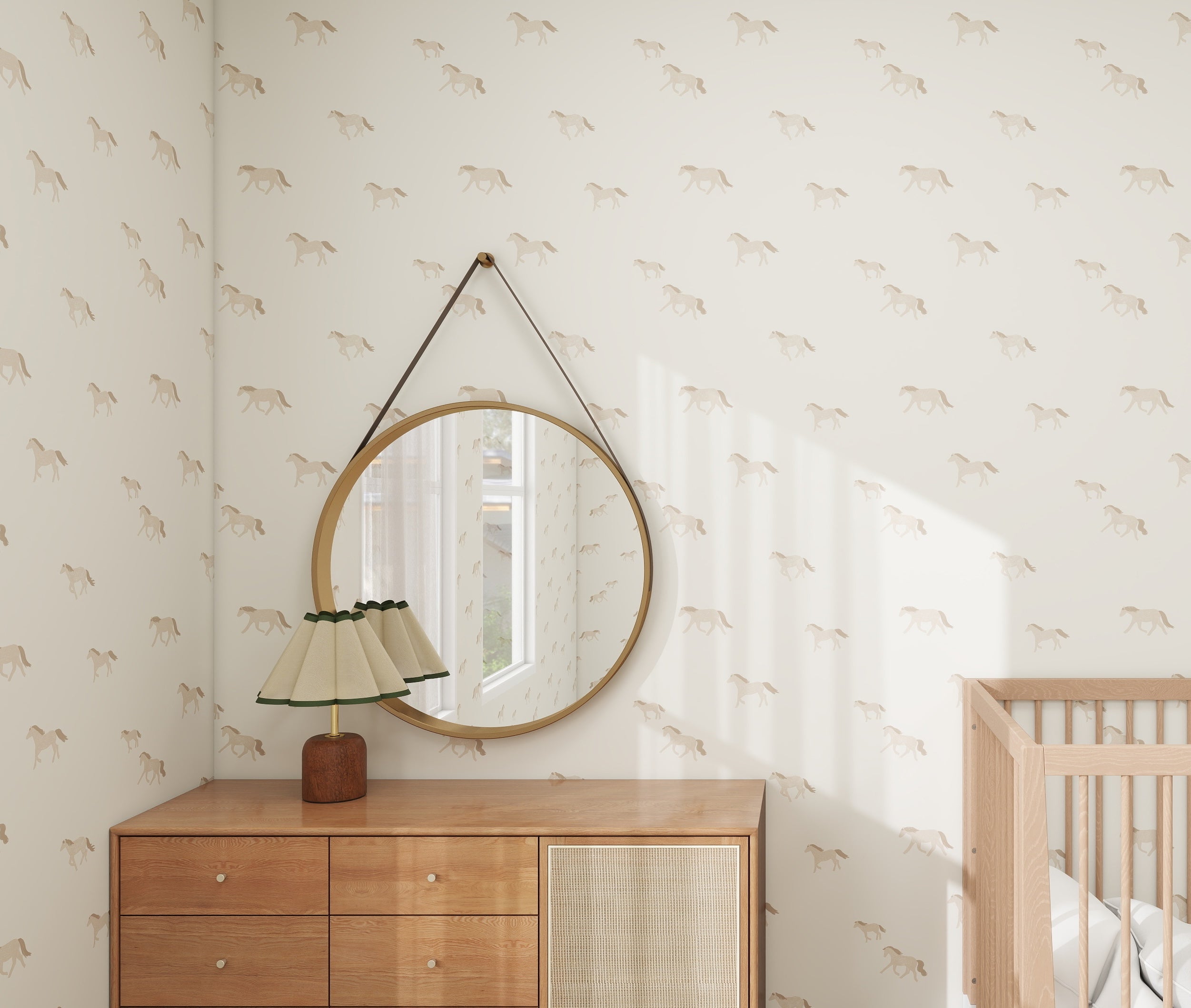 The nursery exudes tranquility with its Winter Wild Horses Wallpaper Repeat Pattern by munks and me, showcasing light brown horses. A round mirror above a wooden dresser with a pleated lamp shade and a nearby crib enhance the calming, stylish atmosphere.