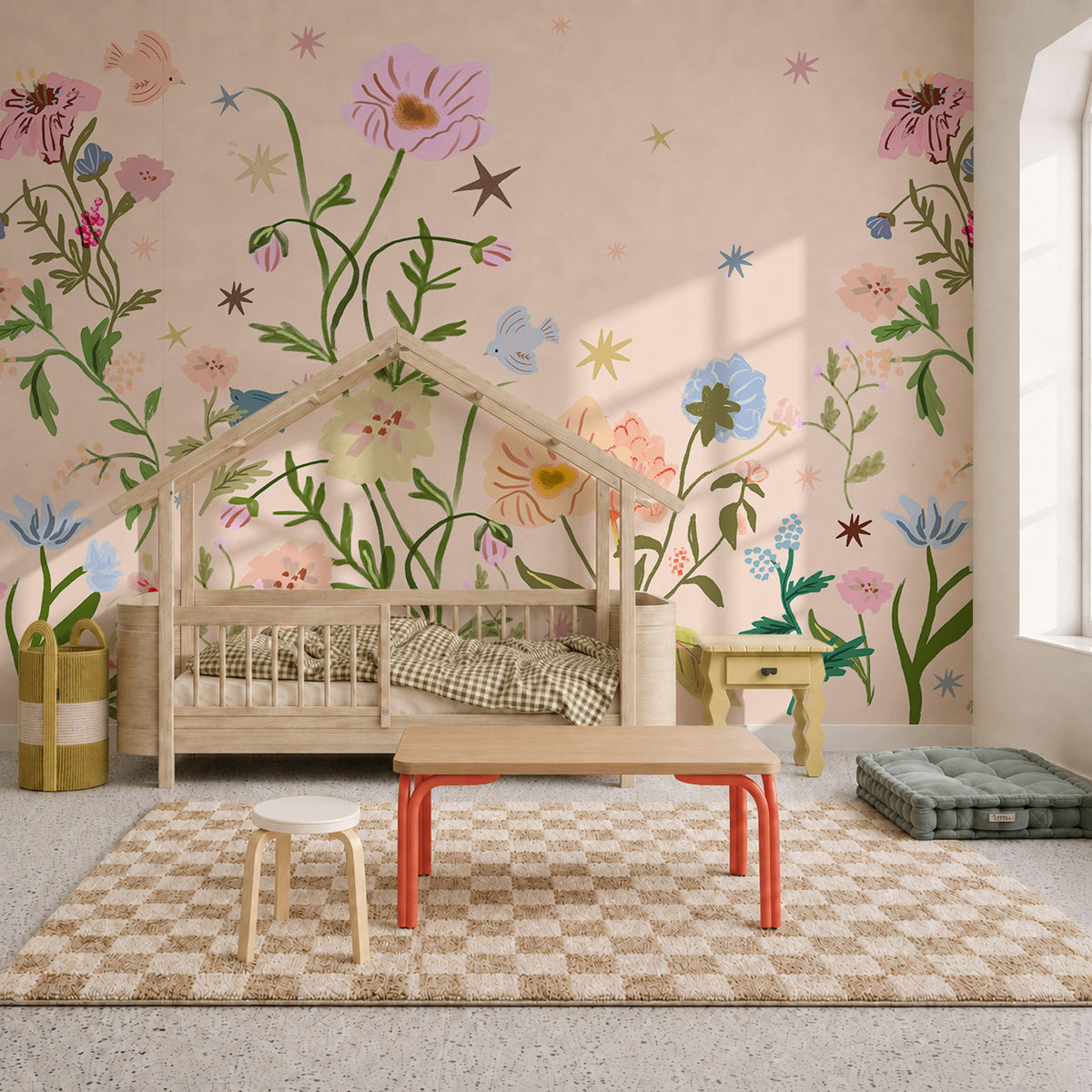 A child’s bedroom featuring The Wishing Garden Pink floral wallpaper mural, a wooden house-shaped bed, a small table with a stool, and a checkered rug.