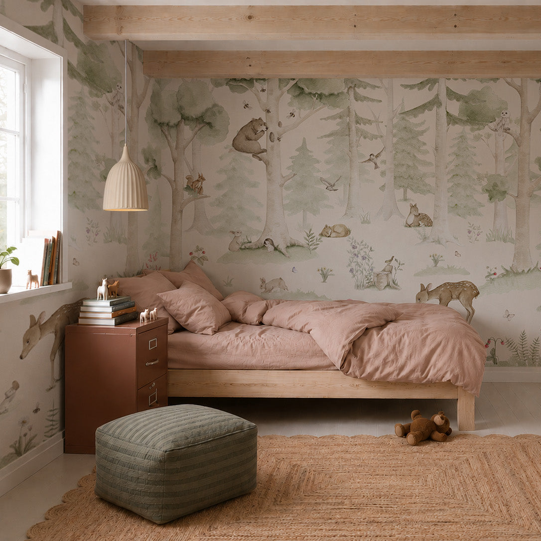 Cozy bedroom with a wooden bed, pink bedding, a green pouf, and a jute rug. The walls are decorated with the Woodland Friends Mural featuring trees and woodland animals. Light streams in from a window.
