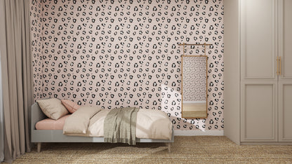 A stylish bedroom with a single bed, light bedding, and a textured throw blanket. The wall features Leopard Print Wallpaper Repeat Pattern | Pink, quirky design, a hanging woven piece, and a wardrobe with beige doors on the right.