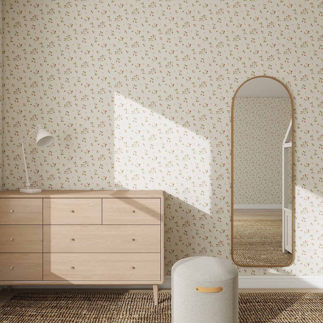 A bright room decorated with Berry and Bramble Wallpaper Repeat Pattern | Sample, featuring a light wood dresser, white table lamp, oval mirror, round stool, and woven rug. Sunlight enhances the wallpapers color and casts gentle shadows.