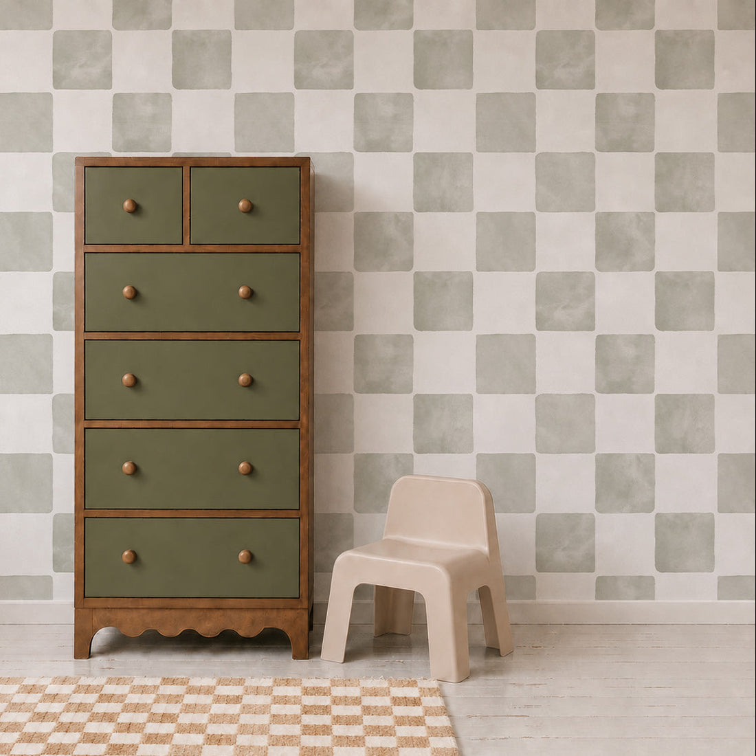 A green and wood dresser stands next to a small beige chair, with a checkered rug on the floor and stylish Billys Checkered Wallpaper in Sage as the background, creating a charming wall decor accent for the room.