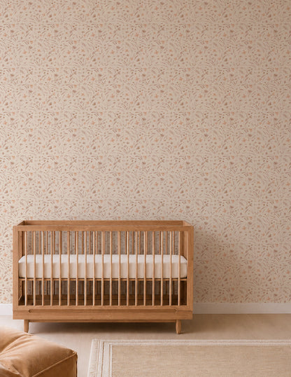 Minimalist nursery with a wooden crib, Butterfly Meadowland Wallpaper in Dune, a tan rug, and a soft brown armchair partially visible on the left. The room features a calm, neutral color palette.