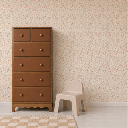 A brown wooden dresser stands next to a small beige chair on a light wood floor, with Butterfly Meadowland Wallpaper in Dune adding a touch of nature and a checkered rug completing the room.