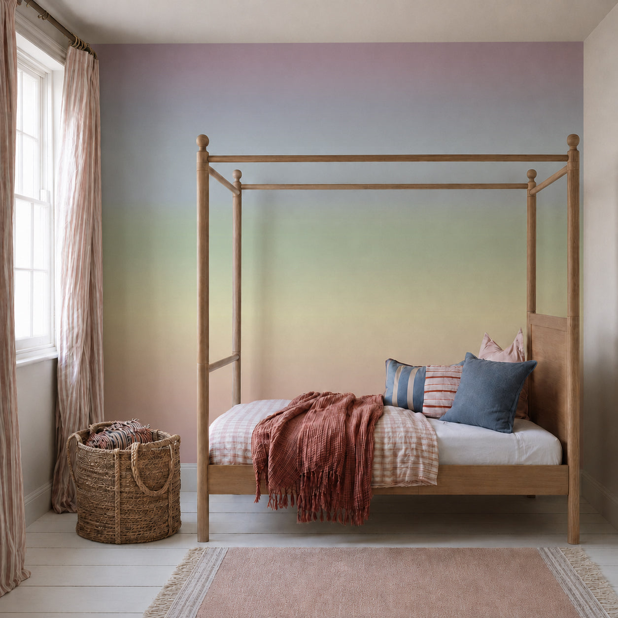 A wooden four-poster bed with colorful pillows and a textured blanket sits in a bright room featuring the Ombre Mural, Rainbow wallpaper, which creates a stunning pastel gradient behind it. A woven basket rests by the window, enhancing the vibrant atmosphere.