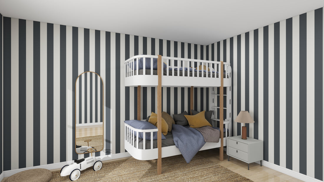 The childrens room displays a sample of munks and mes Circus Stripe Wallpaper Denim with white bunk bed featuring gray bedding, yellow accents, round mirror, lamp on nightstand, woven rug, and toy vehicle. The decor is modern, bright, and playful with black and white vertical stripes.