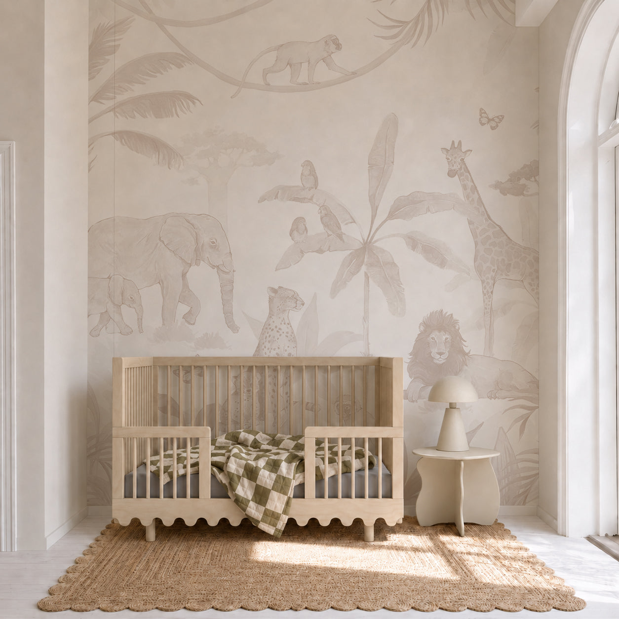 A neutral-toned children’s room features a wooden crib, checkered blanket, small chair, and a jute rug, highlighted by the African Safari Mural, Neutral—a captivating nursery wall covering adorned with elephants, giraffes, lions, and monkeys amidst lush tropical plants—creating the perfect safari-inspired effect for your little one’s space.