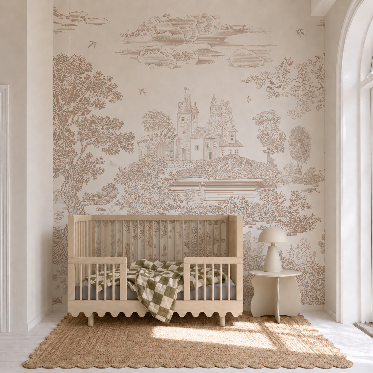 A neutral-toned nursery featuring a wooden crib, green checkered blanket, jute rug, small table, lamp, and the stunning “Forest Hideaway Mural, Neutral” depicting a scenic countryside with trees and a castle.
