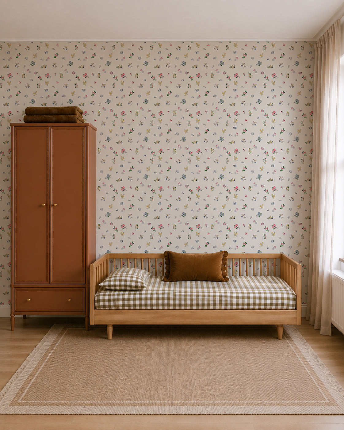 A cozy, minimalist bedroom with a daybed featuring checked bedding, a brown cushion, a rust-colored wardrobe, Powdered Petals Wallpaper with hand-drawn florals, a beige rug, and a large window with light curtains.