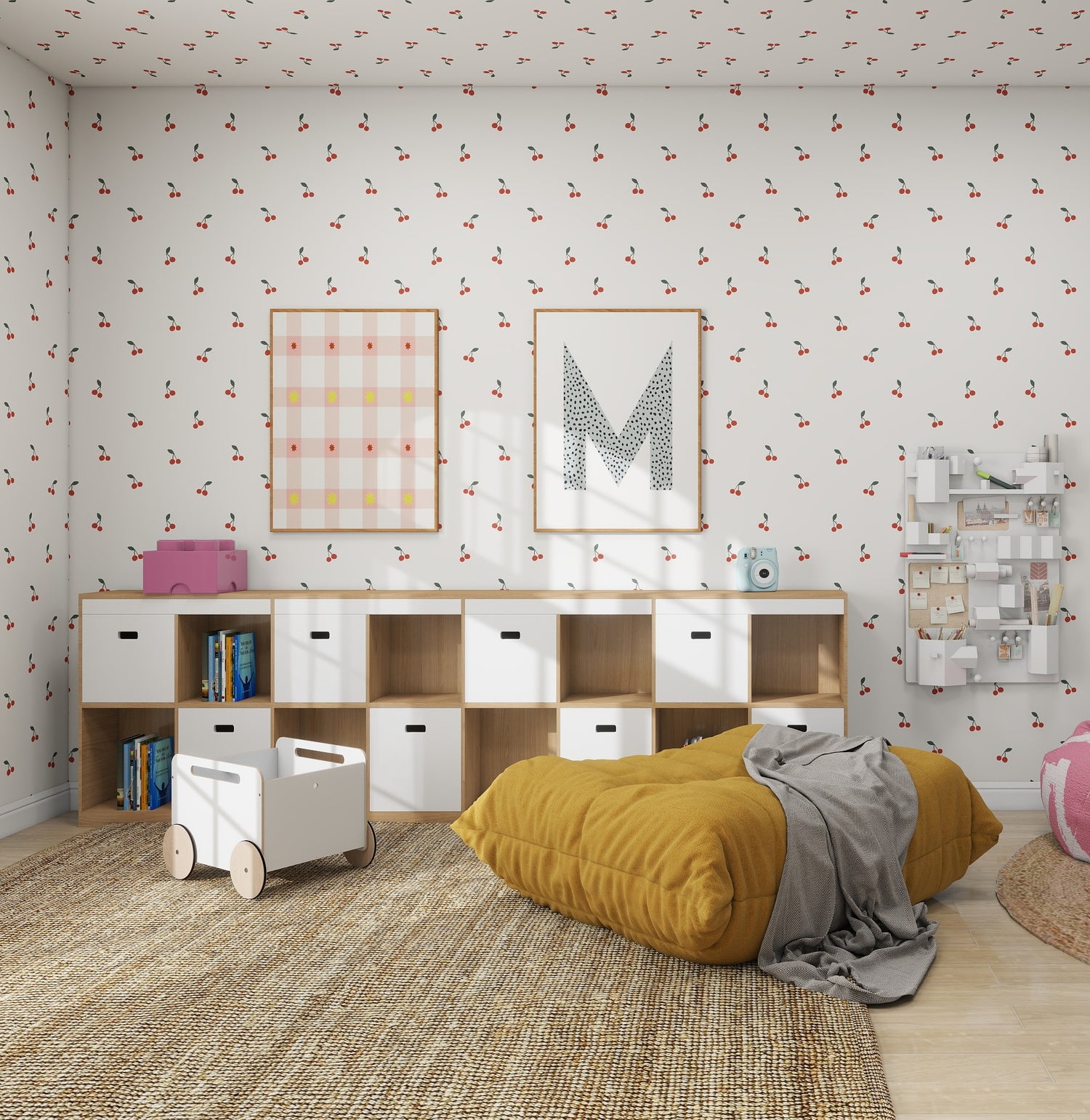 The childrens playroom showcases munks and mes Cherry Sprinkle Wallpaper Repeat Pattern for a timeless design. A wooden shelving unit with white bins stores books and toys, while a mustard cushion and gray blanket rest on the floor. Two framed pictures decorate the wall, complemented by a nearby white cart.