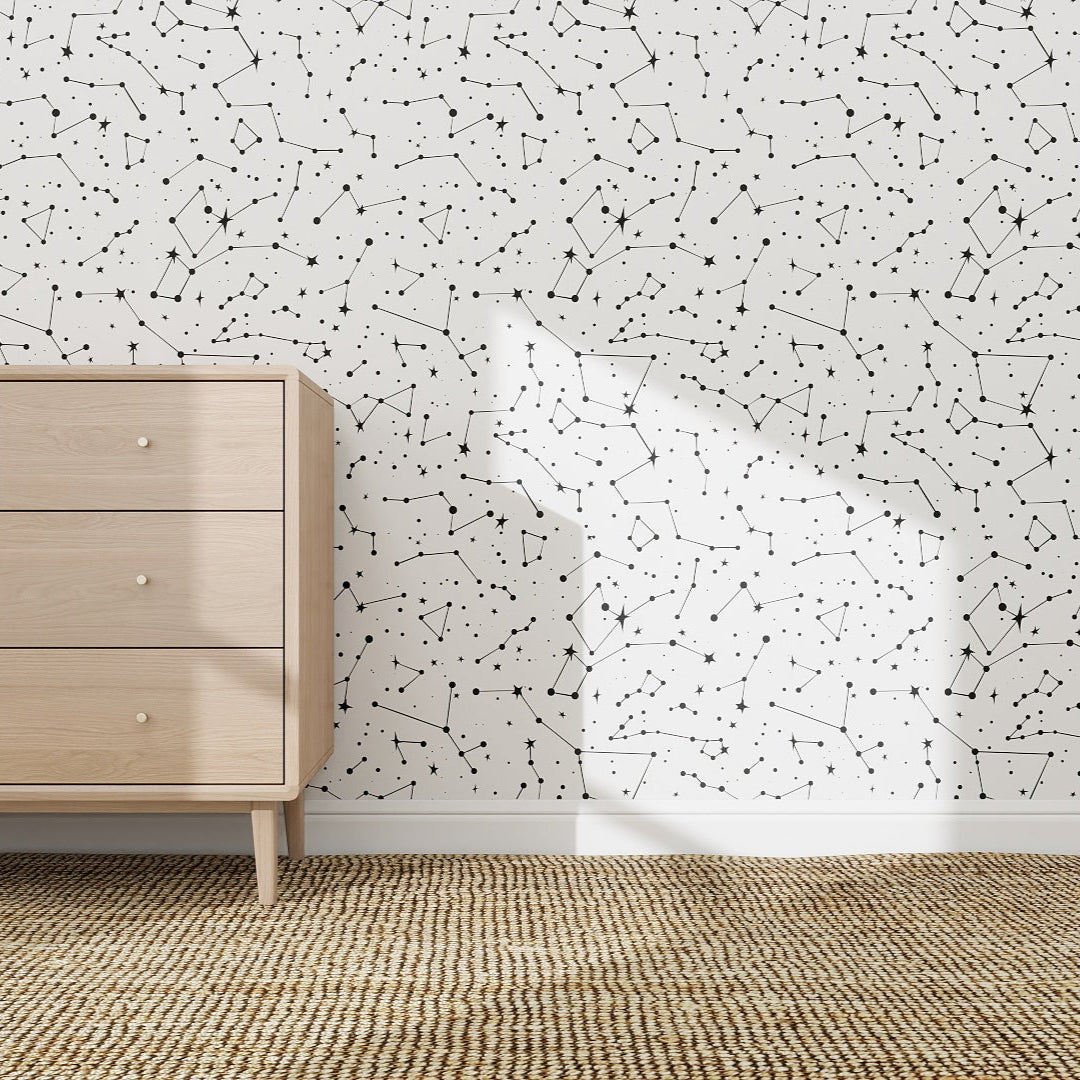 A mid-century wooden dresser stands against a wall finished with Constellation Wallpaper Repeat Pattern, bringing unique style to the space as sunlight creates gentle shadows and a woven rug warms up the modern room.