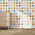 Rainbow Squares Wallpaper Repeat Pattern adds color and creativity to your space. Here, it decorates a wall beside a light wood dresser on a woven rug, while sunlight highlights the pastel squares’ playful design.