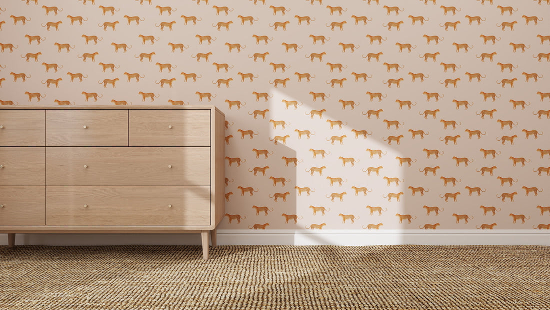 A light wood dresser sits on a woven rug against a wall decorated with quirky Goldies Cheetah Repeat Pattern Pink wallpaper. Sunlight casts a window-shaped shadow on the wall.