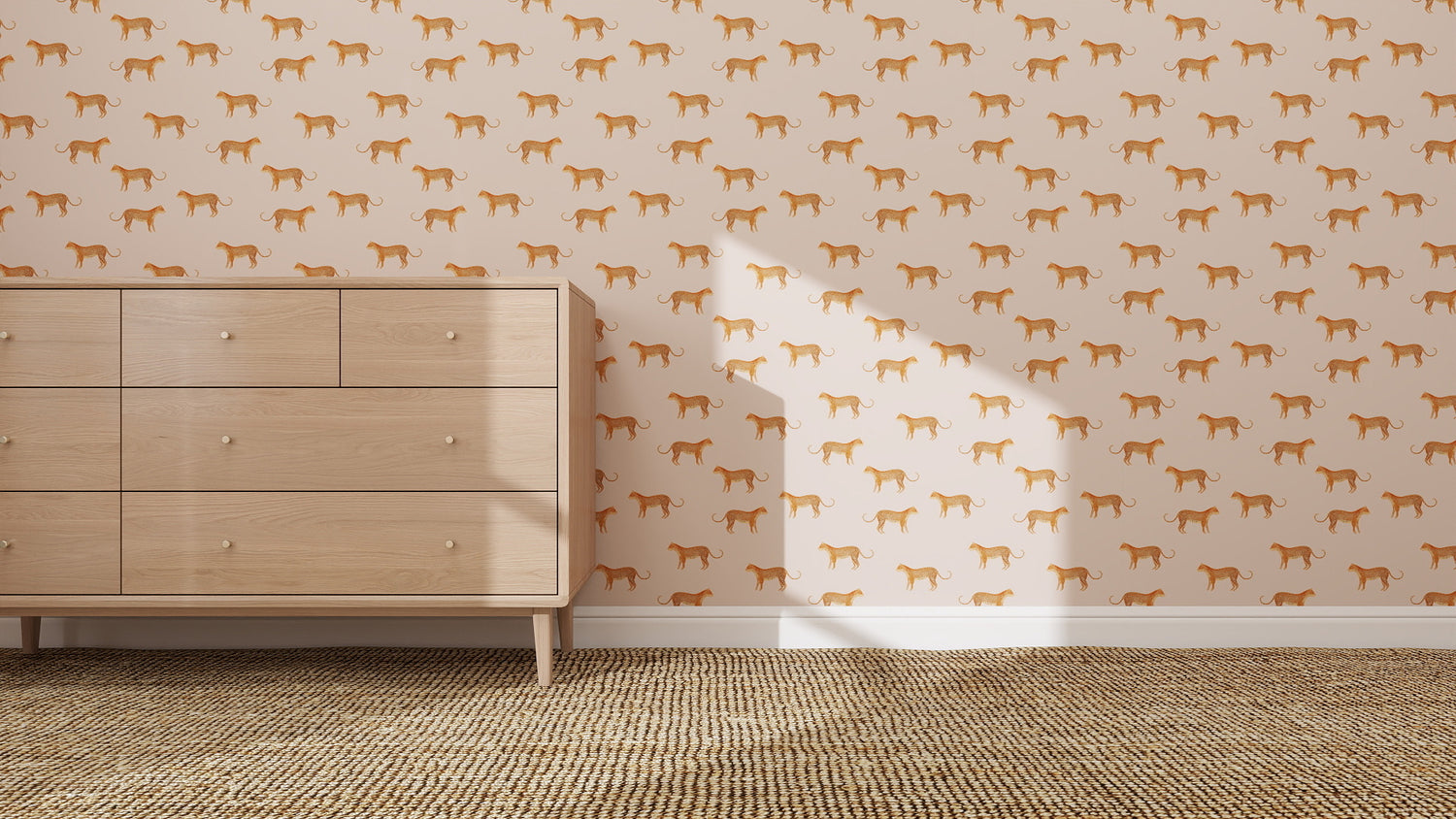 A light wood dresser sits on a woven rug against a wall decorated with quirky Goldies Cheetah Repeat Pattern Pink wallpaper. Sunlight casts a window-shaped shadow on the wall.