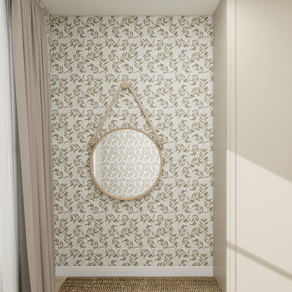 A round mirror with a leather strap hangs on a wall covered in Dreamy Vines Wallpaper Repeat Pattern, highlighting its beautiful leafy beige and white design. Beige curtains and a woven mat create a cozy, natural-toned corner.