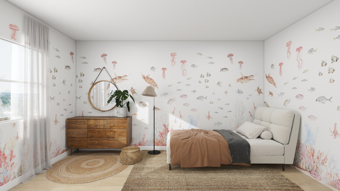 A childrens bedroom styled like an aquatic realm features the Fish Tank Wallpaper Mural by munks and me, showcasing sea creatures like fish, turtles, and jellyfish. The room includes a white bed with a brown blanket, round mirror above a wooden dresser, woven rug, and large window with sheer curtains.