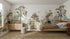 A cozy bedroom features the Into The Forest Wallpaper Mural Sample in stunning quality, showcasing trees, deer, foxes, owls, and butterflies. Sunlight streams onto the bed, nightstand, dresser, and woven rug through a large window.