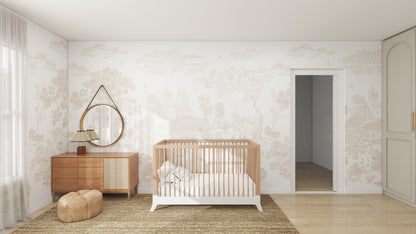 A minimalist nursery features a wooden crib with white bedding, a wooden dresser below a round mirror, and a woven rug. The walls are adorned with Forest Hideaway Wallpaper Neutral, creating the ideal backdrop, while sheer curtains allow natural light to stream through the window.