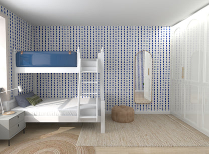 A bedroom features munks and mes Jolly Jester Wallpaper in royal blue and white patterns, a white bunk bed with an unmade lower bunk, a round beige pouf, a rug, nightstand with lamp, and arched mirror. The vibrant colors enhance the tranquil aesthetic.