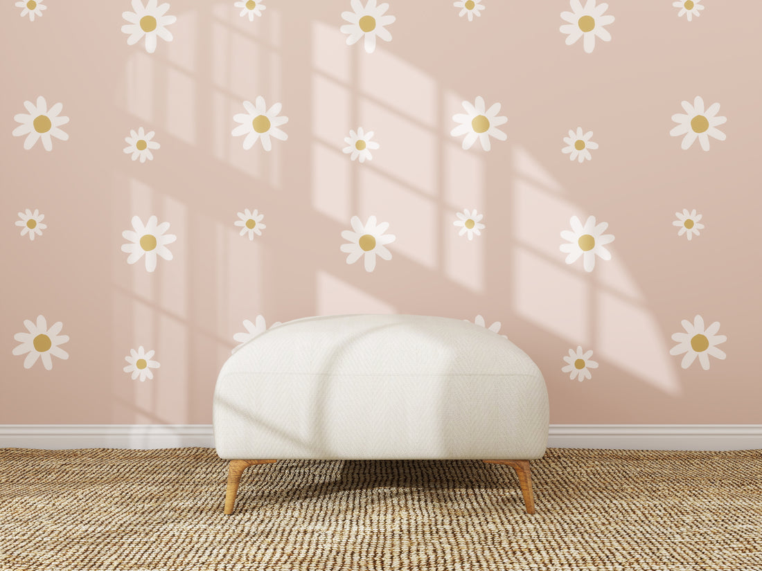 A white ottoman sits on a woven rug before a pink wall featuring the Custom Large Daisy Floral Wallpaper Repeat Pattern. Sunlight pours in, casting shadows and accentuating the wallpaper’s playful daisy motifs.