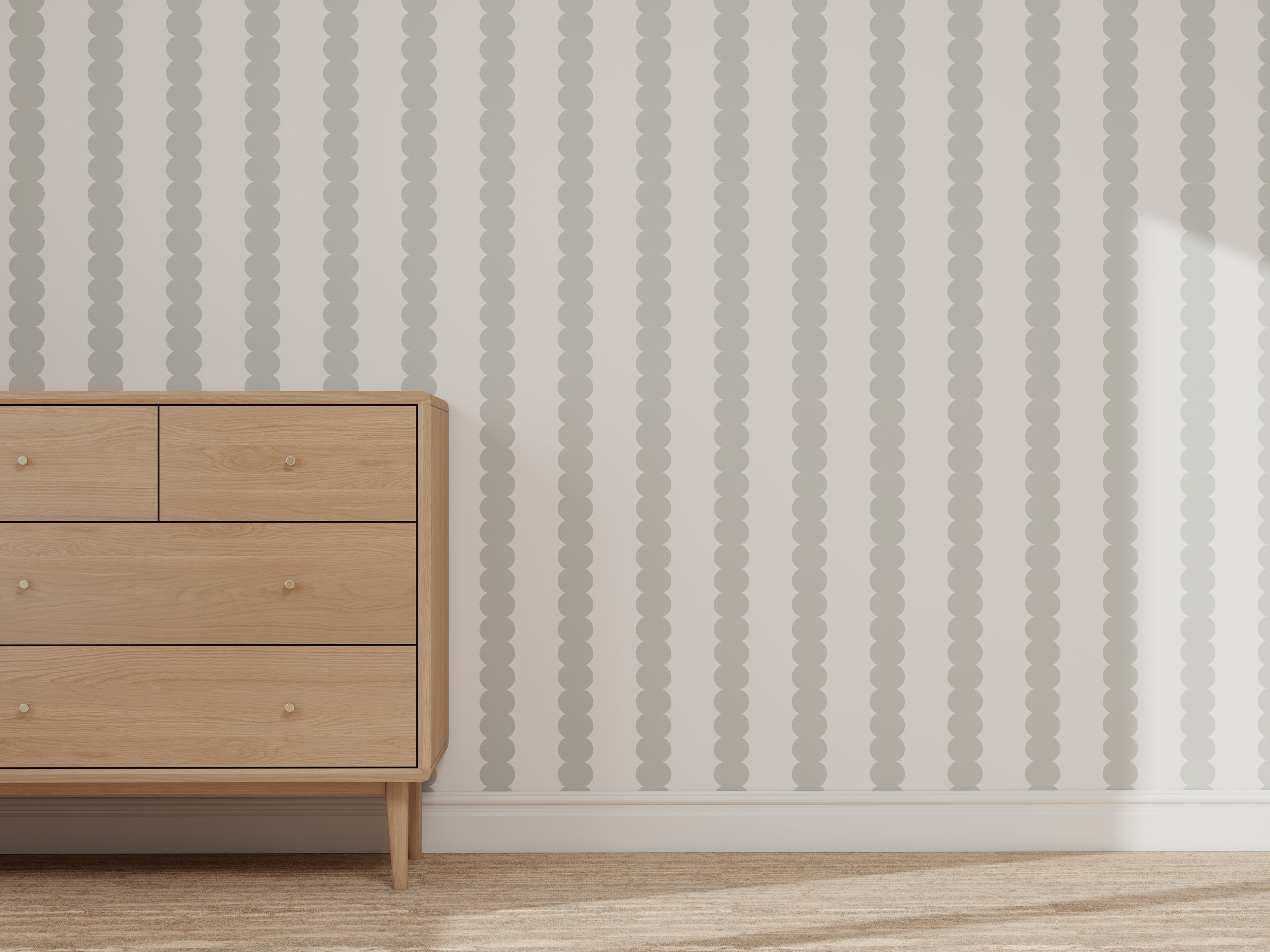 A light wooden dresser with four drawers stands against a wall featuring the Custom Scallop Stripe Wallpaper Blue sample. Sunlight illuminates the right side, and a light-colored rug covers the floor.