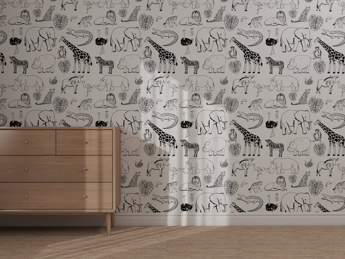 A wooden dresser stands against a wall decorated with the Going on Safari Wallpaper Repeat Pattern sample, which features black-and-white giraffes, elephants, crocodiles, hippos, and leaves. Sunlight highlights the patterned wall.