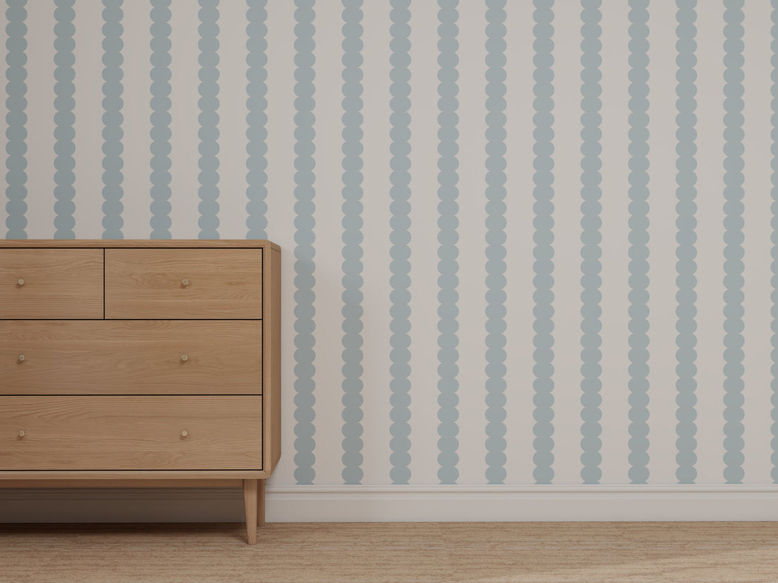 A wooden dresser with six drawers stands on a beige carpet beside a wall covered in Custom Blue Scallop Stripe Wallpaper.