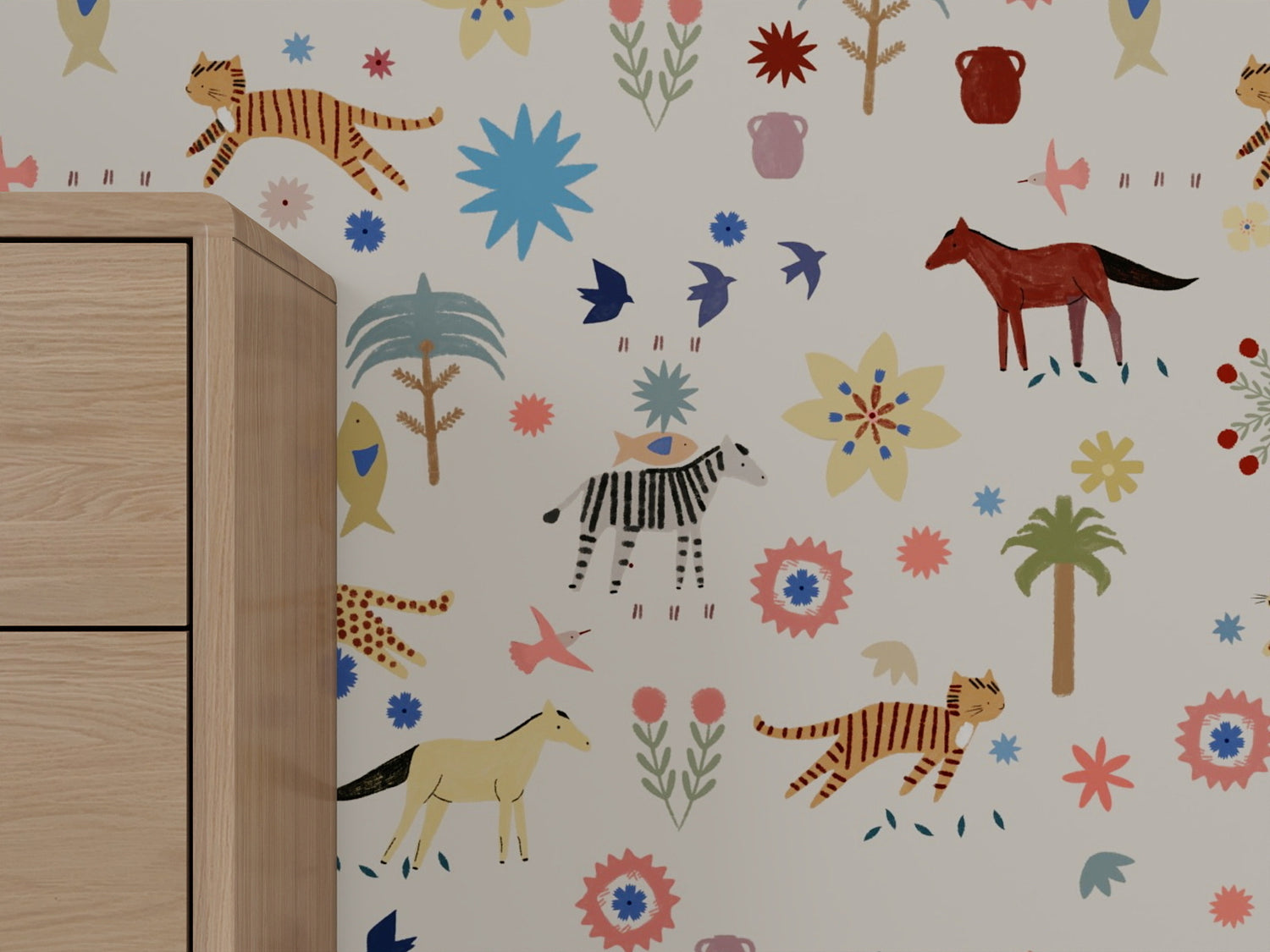 Little Wanderers Wallpaper enlivens nursery walls with vibrant animal and plant illustrations—tigers, zebra, horses, birds, flowers, and trees—for a storytelling look. A light wooden cabinet is visible on the left.