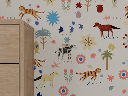 Little Wanderers Wallpaper enlivens nursery walls with vibrant animal and plant illustrations—tigers, zebra, horses, birds, flowers, and trees—for a storytelling look. A light wooden cabinet is visible on the left.