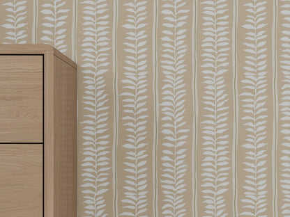 A light wood furniture piece stands beside a beige wall covered in Meadow Leaf Stripe Wallpaper, Clay, adding a modern and nature-inspired touch to the space.