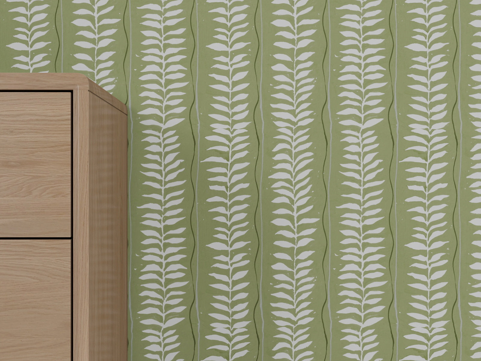 A light wooden cabinet stands against a green wall decorated with Meadow Leaf Stripe Wallpaper, Sage, which features a repeating white leaf pattern. The cabinet is partially visible on the left side of the image.