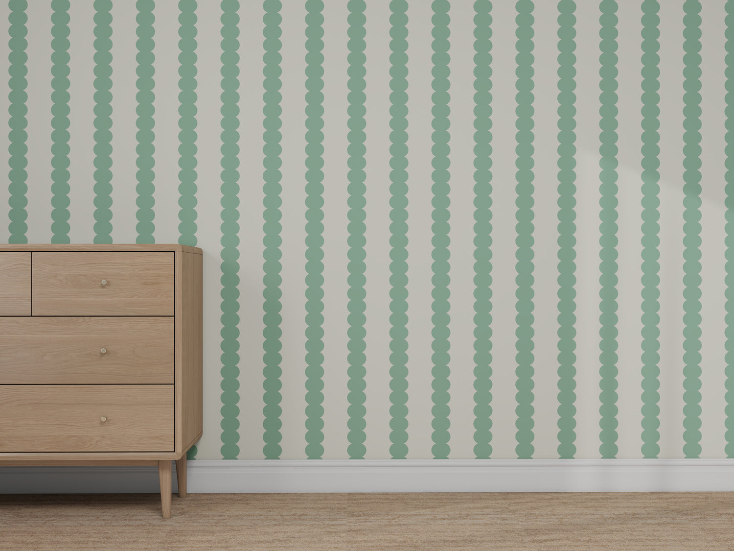 A light wood dresser stands in front of a wall covered with Custom Green Seafoam Scallop Stripe Wallpaper | Sample. The wallpaper features vertical mint green scalloped stripes on a light background, and the floor is carpeted in light tan.