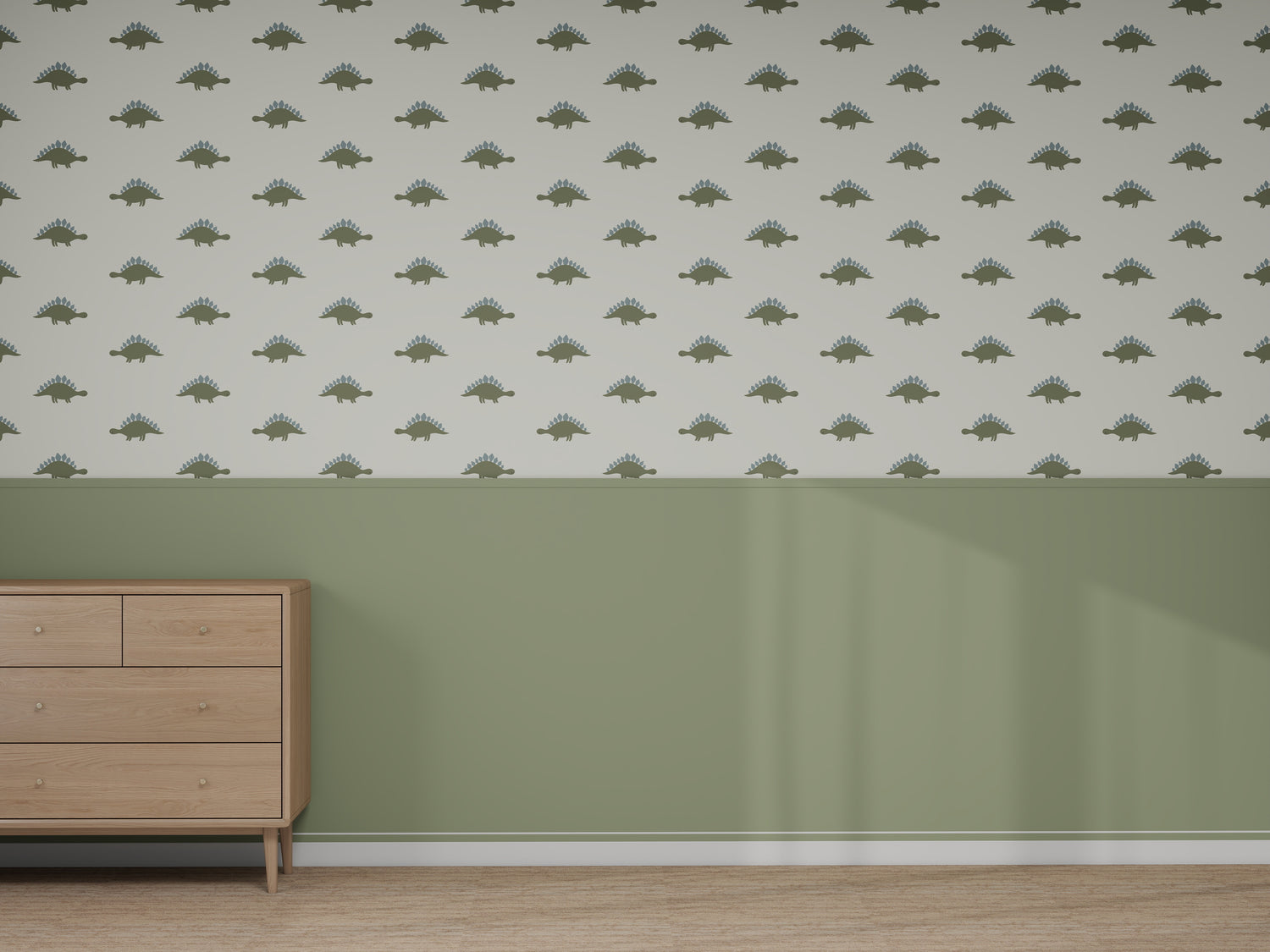 A room features light wood floors, sage green lower walls, and a "Custom Otis Dinosaur 2 | Sample" wallpaper with green dinosaur shapes above. A light wood dresser stands on the left as sunlight highlights the space’s colors and quality.