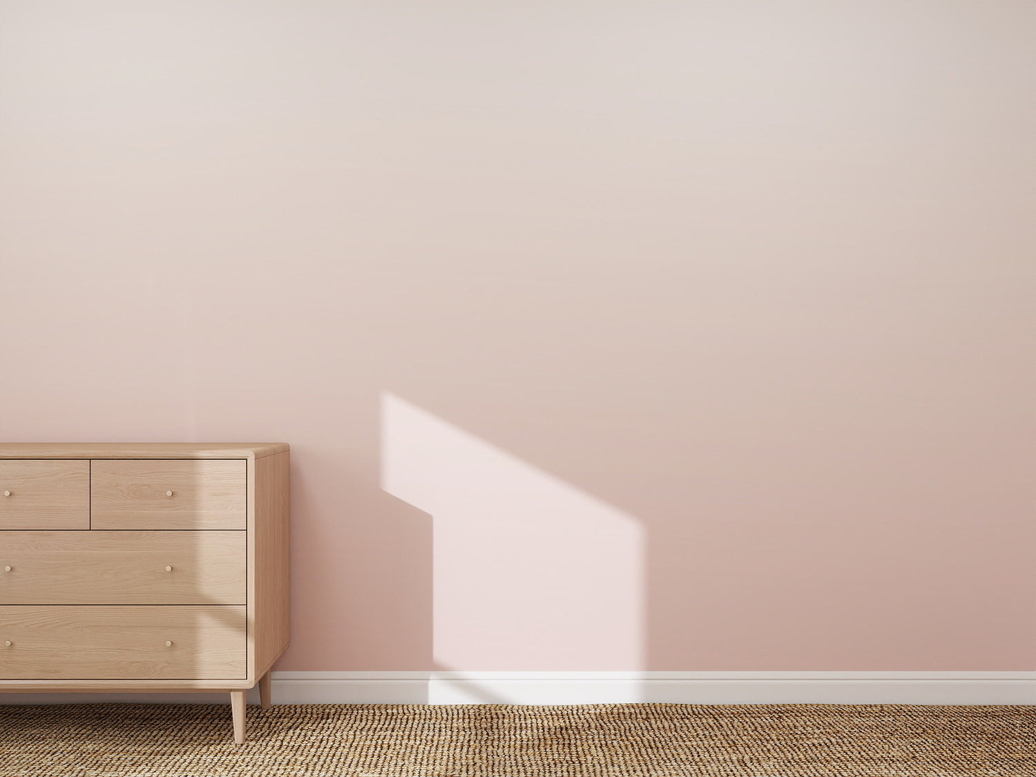 A minimalist room featuring the Ombre Wallpaper Mural | Pink, a light wooden dresser on the left, sunlight casting window-shaped shadows, and a woven beige rug on the floor.