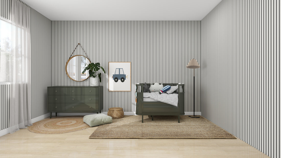 A modern nursery features munks and mes Pinstripe Wallpaper Charcoal, a green crib, and dresser. A circular mirror and car picture decorate the walls. A jute rug and pillow are on the light wood floor, with a standing lamp illuminating the space while sunlight streams through a window.