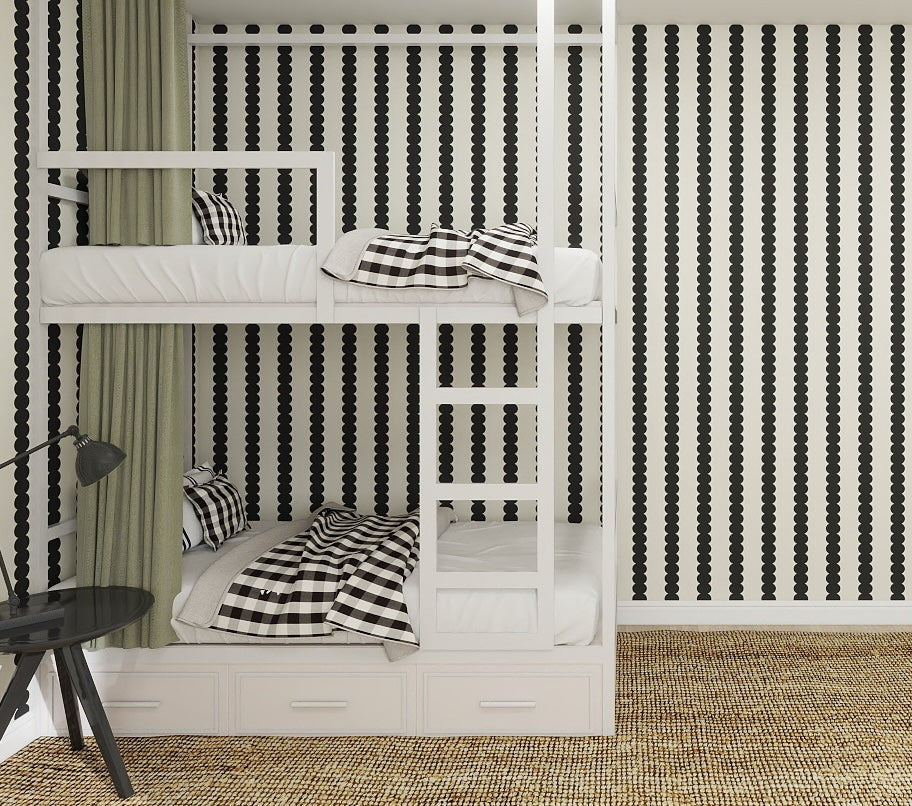 A white bunk bed with black-and-white checkered bedding is set against a wall featuring Scallop Stripe Wallpaper Charcoal, creating a timeless monochrome look. The scene is finished with woven-texture flooring and a small black table with lamp.