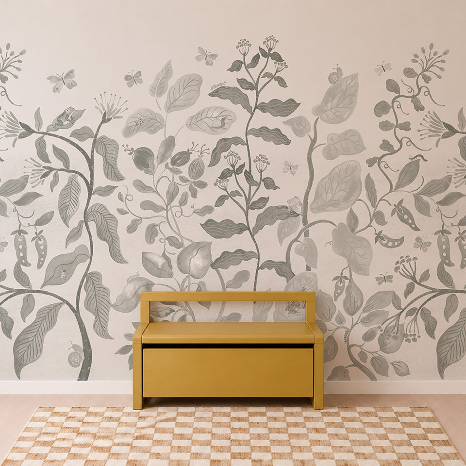 A mustard yellow bench sits on a checkered beige rug in front of a wall adorned with the Secret Garden Mural in Sage—a large, grayscale botanical mural featuring various leaves, flowers, and insects.
