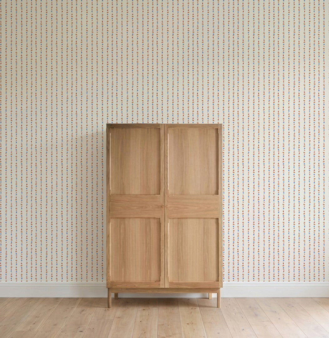A light wooden cabinet with four panels stands on a wooden floor against a wall adorned with All I See Is Magic Stripe Wallpaper, featuring vertical lines of small colored dots.