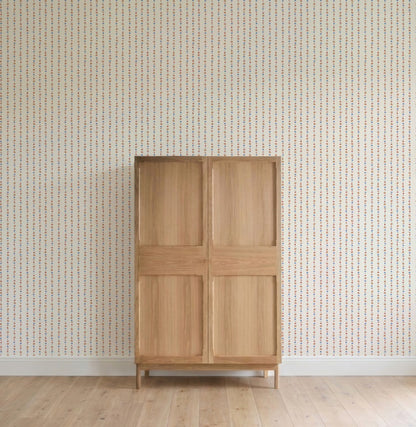 A light wooden cabinet with four panels stands on a wooden floor against a wall adorned with All I See Is Magic Stripe Wallpaper, featuring vertical lines of small colored dots.