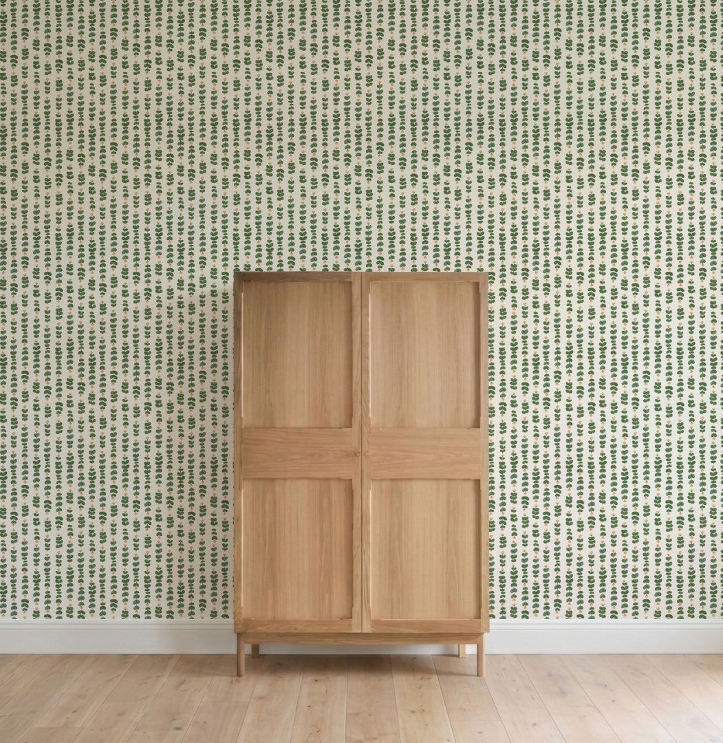 A light wooden cabinet stands on a light wood floor against a wall covered with Floral Trails Wallpaper featuring a small green leaf pattern in rows.